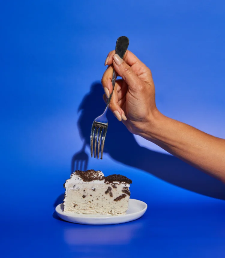Hand with fork and ice cream cake
