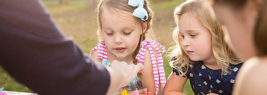 Girls about to blow candles out on birthday ice cream cake