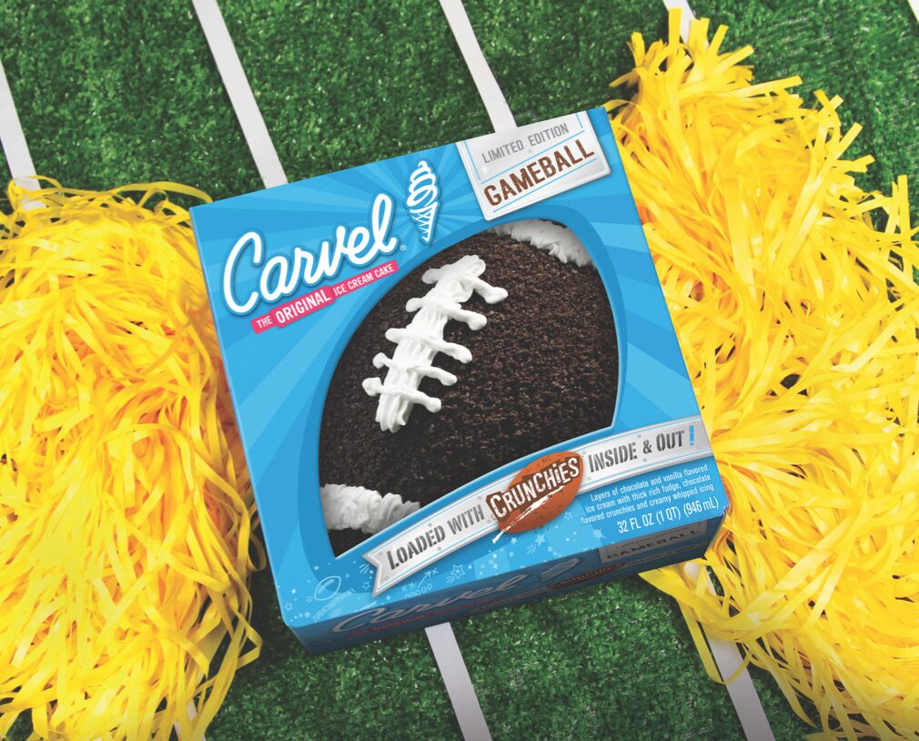 Carvel Gameball Football cake loaded with crunchies inside and out on a turf background with yellow pom poms