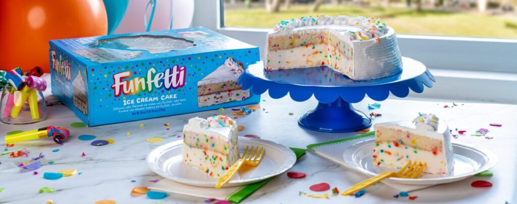 Funfetti Ice Cream Cake on a cake plate on top of a table with other party accessories